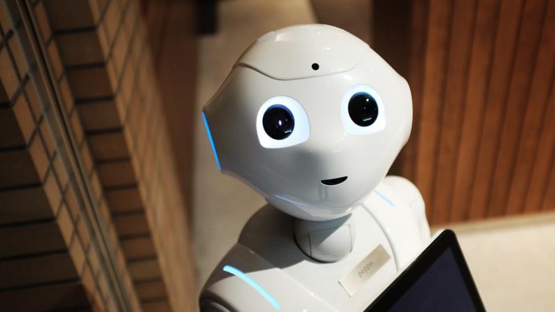 A small white robot holding a tablet