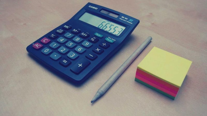 A calculator, pen and sticky notes on a desk