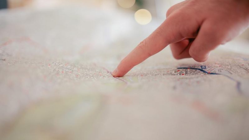 A finger pointing to a location on a map